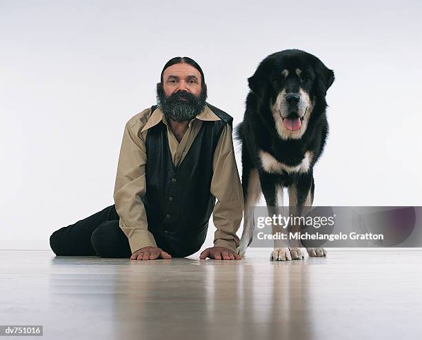 portrait of a bearded man sitting next to a tibetan mastiff - tibetan mastiff stockfoto's en -beelden