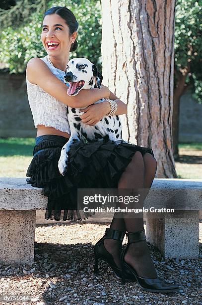 woman sitting on a park bench holding her dalmatian - pampered pets stock pictures, royalty-free photos & images