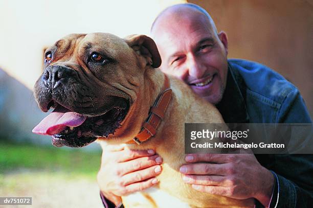 portrait of a man with his arms around a staffordshire bull terrier - djurtunga bildbanksfoton och bilder