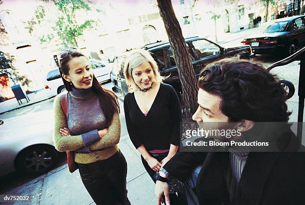 two women talking to a man on the street - women talking stock pictures, royalty-free photos & images