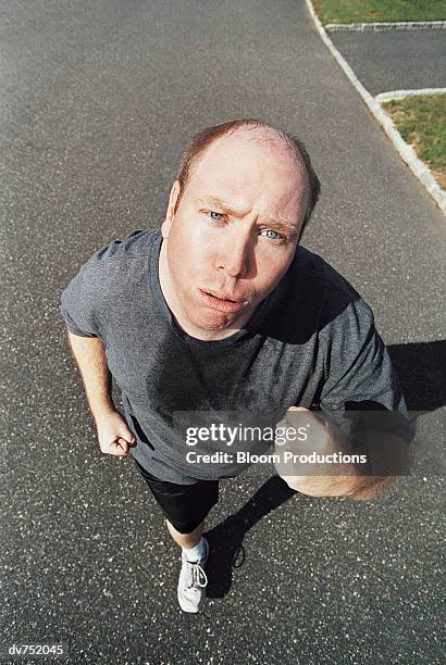portrait of a man jogging along the road - sweat stains stock pictures, royalty-free photos & images