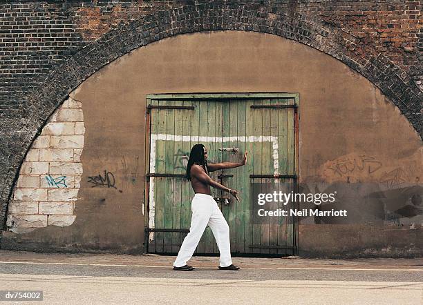 side view of man practicing tai chi - tai stock pictures, royalty-free photos & images