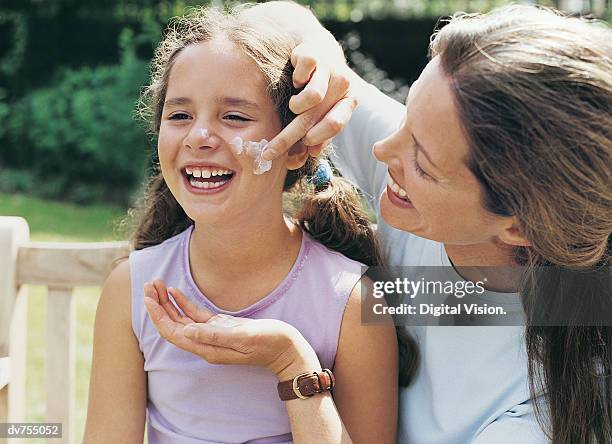 mother applying suntan lotion to her daughter - applying sunscreen stock pictures, royalty-free photos & images