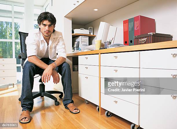 portrait of a serious businessman sitting in a home office - black hair dresser stock pictures, royalty-free photos & images