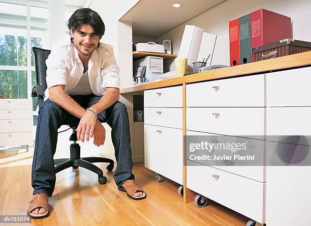 portrait of a casually dressed businessman sitting in his home office - black hair dresser stock pictures, royalty-free photos & images