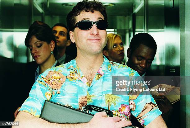businessman standing in a lift wearing sunglasses and an unconventional shirt - hawaiian shirt 個照片及圖片檔