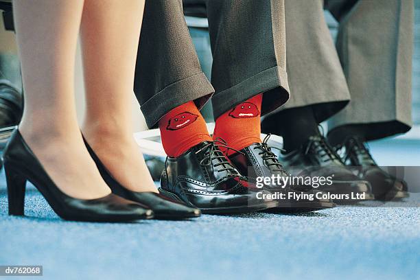 businessman wearing individualistic socks between two of his colleagues - business shoes stockfoto's en -beelden