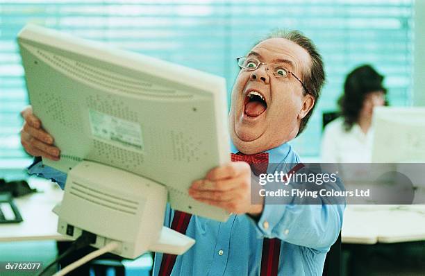 surprised businessman holding a computer monitor in the office - technophile stock pictures, royalty-free photos & images