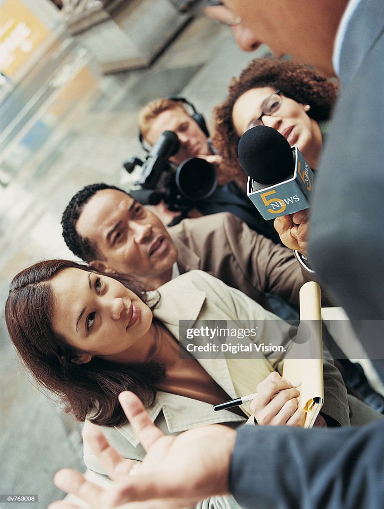 News Reporters and a Cameraman Interviewing a Man