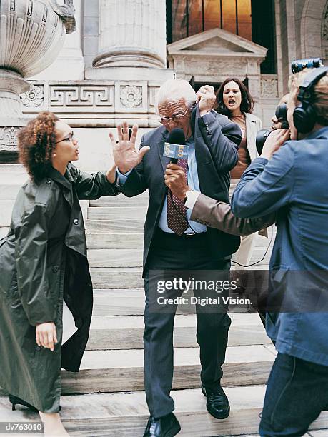 news reporters trying to interview a mature man in a suit on the steps of a building - interview rejection stock pictures, royalty-free photos & images