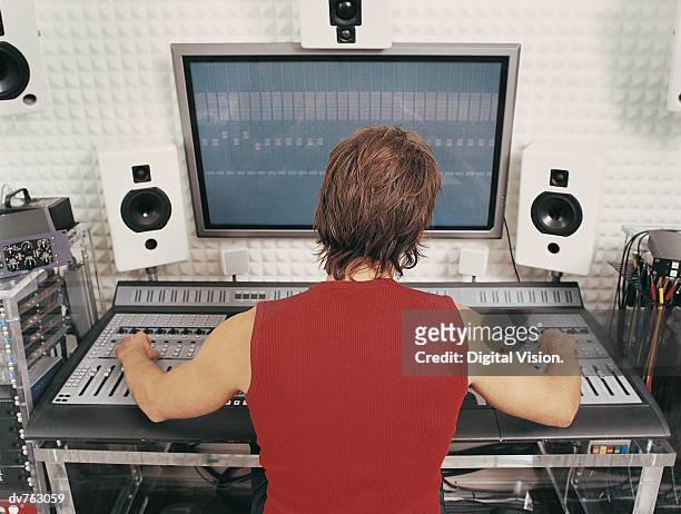 rear view of a producer using sound recording equipment in a recording studio - sound stock-fotos und bilder