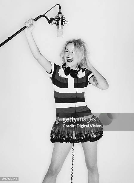 female pop singer laughing and holding a microphone - under the skirt stock pictures, royalty-free photos & images