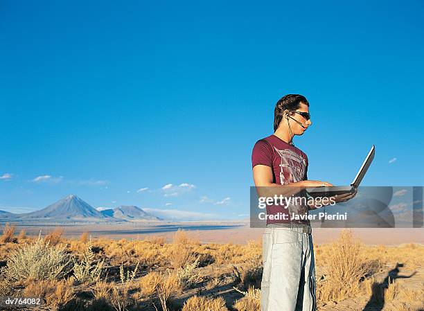 side view of a man using a laptop in the desert - laptop desert stock pictures, royalty-free photos & images