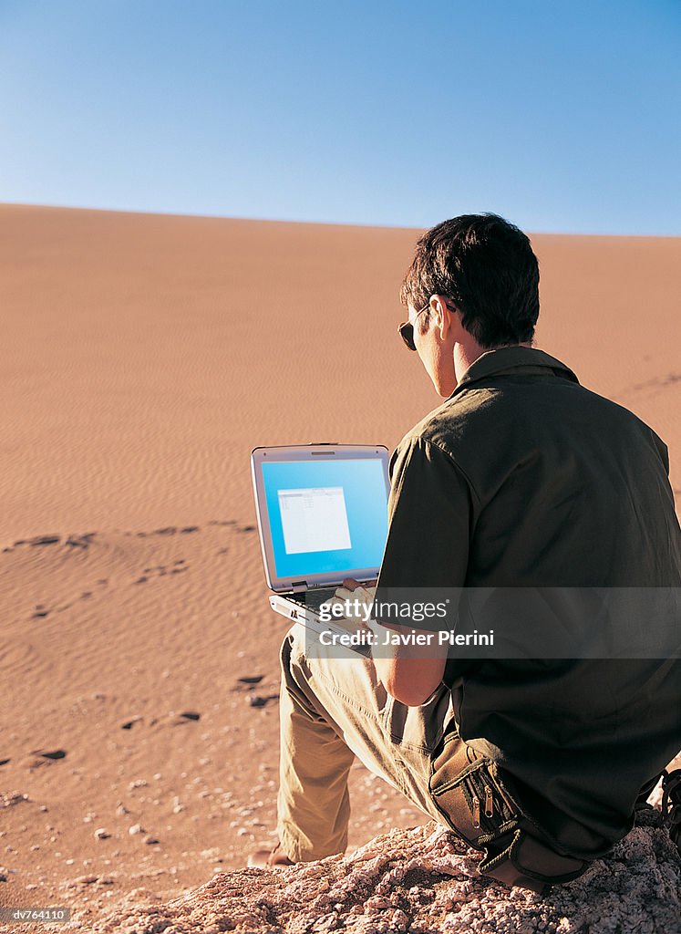 Rear View of Man Using a Laptop in the Desert