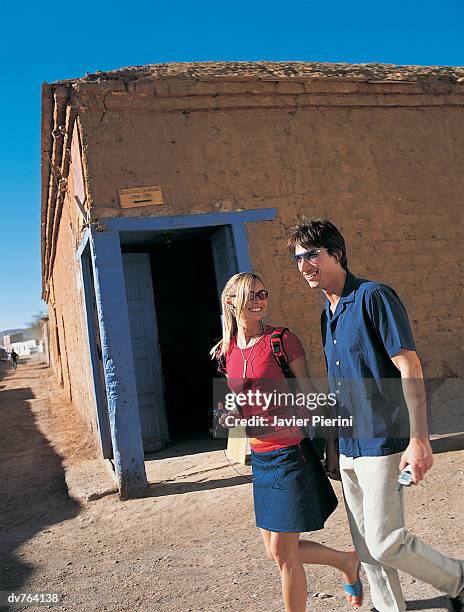 couple with personal stereo and cellphone walking past building - personal stereo stockfoto's en -beelden