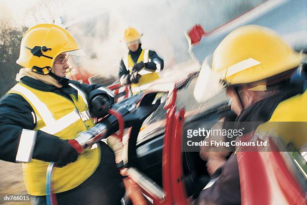 firefighters rescuing an injured man in a mangled car - mangled stock pictures, royalty-free photos & images