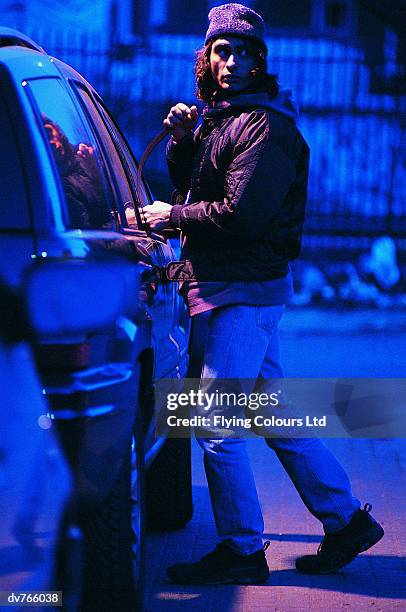 male criminal beaking into a car on a city street - five arrested in delhi after shootout between police and gang of car jackers stockfoto's en -beelden