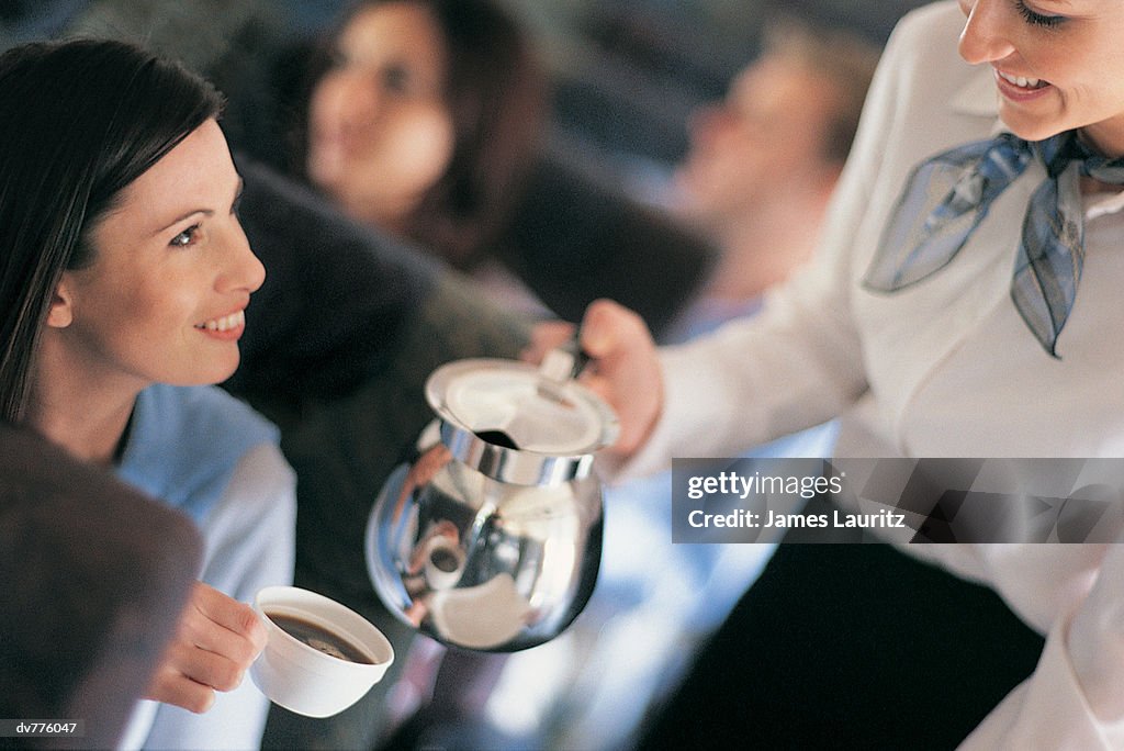 Female Passenger Being Served Coffee By An Air Stewardess