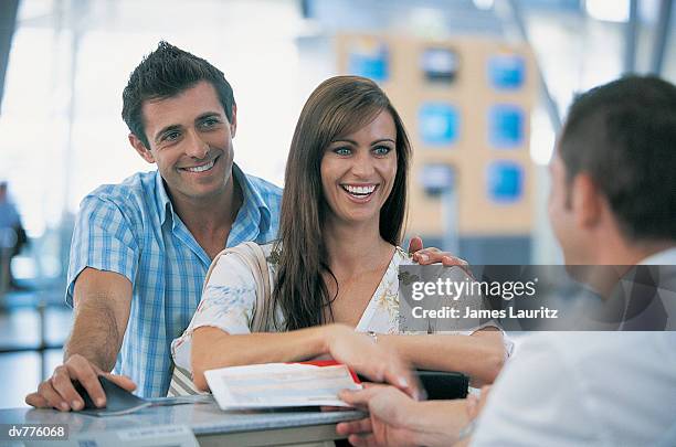 smiling couple showing their tickets at the airport check in - check up ストックフォトと画像