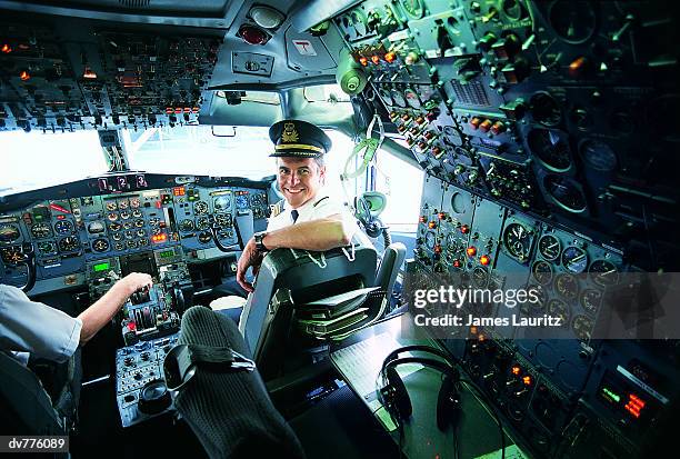 portrait of a pilot sitting at the controls of a commercial aeroplane - airline pilot imagens e fotografias de stock