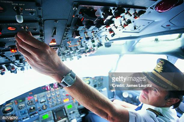 pilot switching a control in the cockpit of a commercial aeroplane - captains stock pictures, royalty-free photos & images