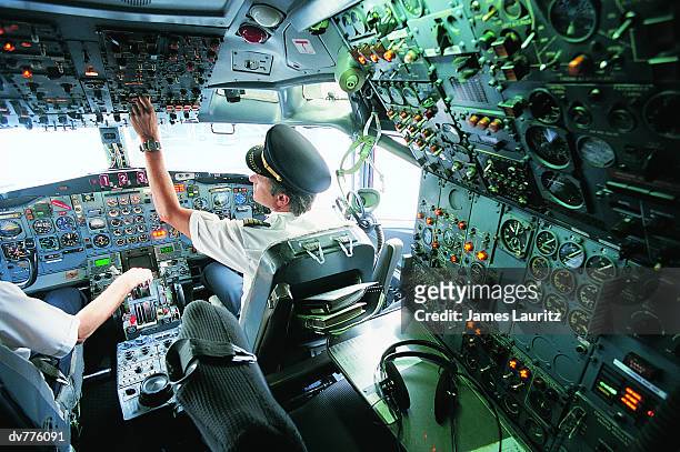 pilot switching a control in the cockpit of a commercial aeroplane - captain hat stock-fotos und bilder