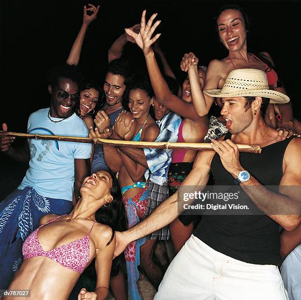 woman doing the limbo at a crowded party - limbo stock-fotos und bilder