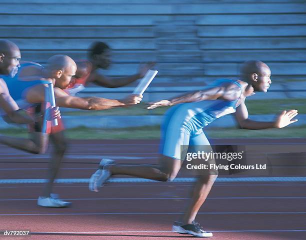 athlete passing the baton in a relay race - pan stock-fotos und bilder