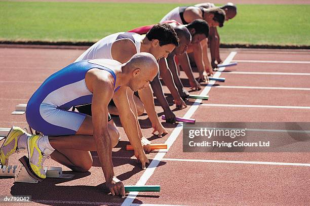 six athletes holding batons at the starting line of a relay race - sports competition format stock pictures, royalty-free photos & images