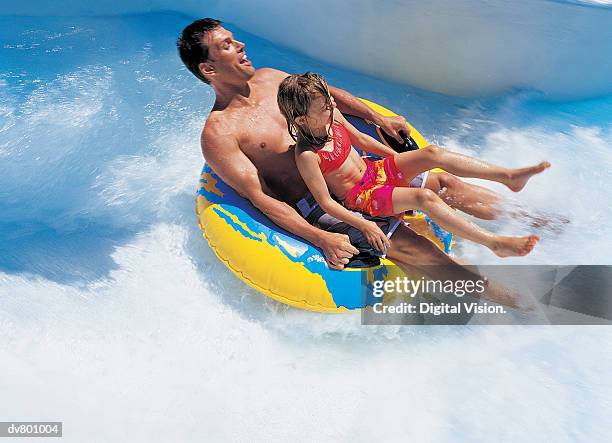 father and daughter on a waterslide - wasserrutsche stock-fotos und bilder