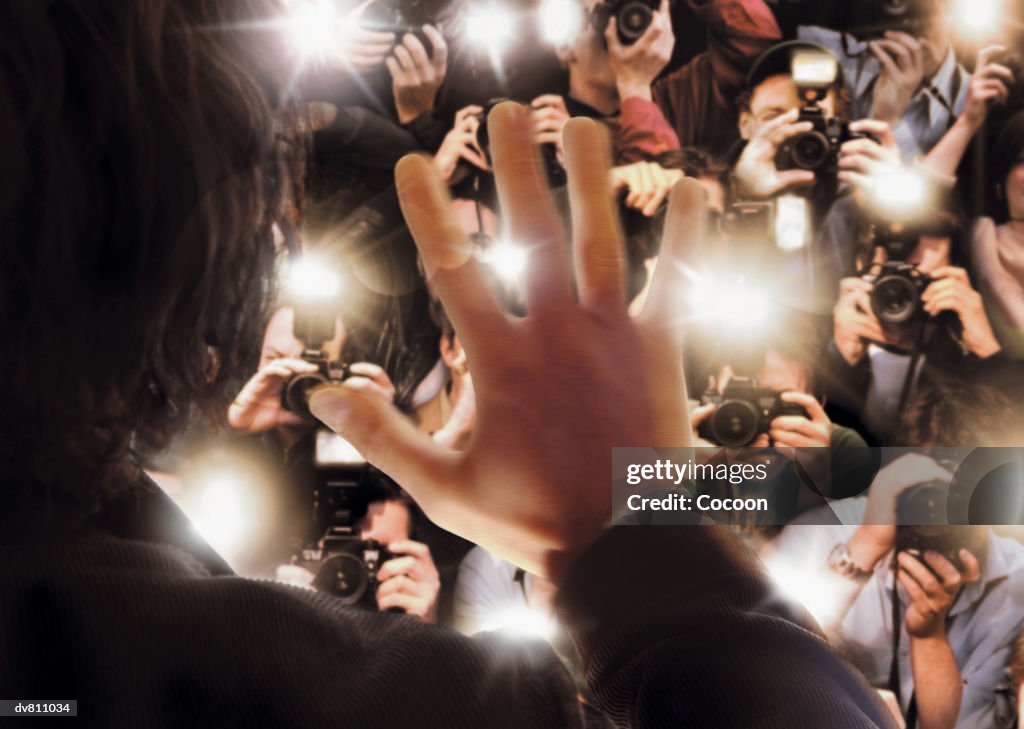 Celebrity Being Photographed By a Large Group of Paparazzi