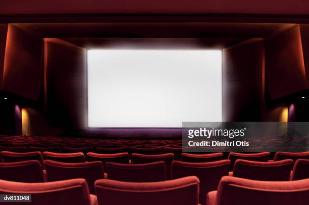 illuminated projection screen in an empty cinema - filmindustrie stock-fotos und bilder