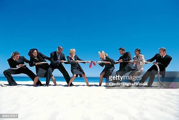 business people playing tug-of-war on the beach - war stock-fotos und bilder