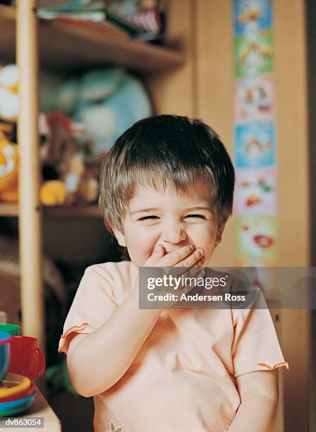 portrait of a preschool girl laughing with her hand covering her mouth - andersen stock pictures, royalty-free photos & images