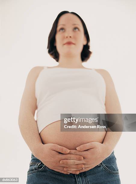 portrait of a pregnant woman holding her hands around her stomach - ross stockfoto's en -beelden