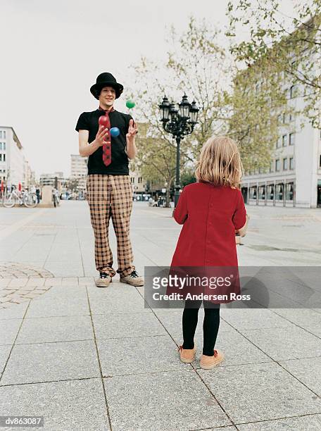 busker showing his juggling skills to a young girl standing on the pavement - andersen ross stockfoto's en -beelden