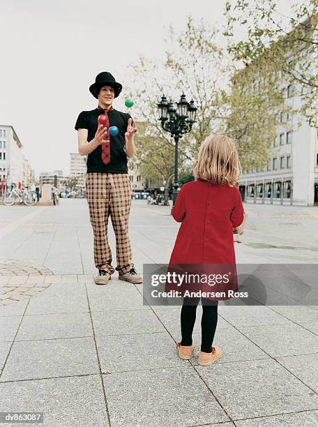 busker showing his juggling skills to a young girl standing on the pavement - ross stock pictures, royalty-free photos & images