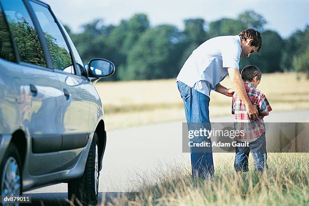 man helping his son to urinate at the side of the road - kids peeing - fotografias e filmes do acervo