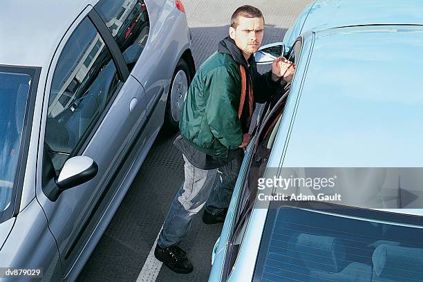 portrait of a man committing car theft in a car park - five arrested in delhi after shootout between police and gang of car jackers stockfoto's en -beelden