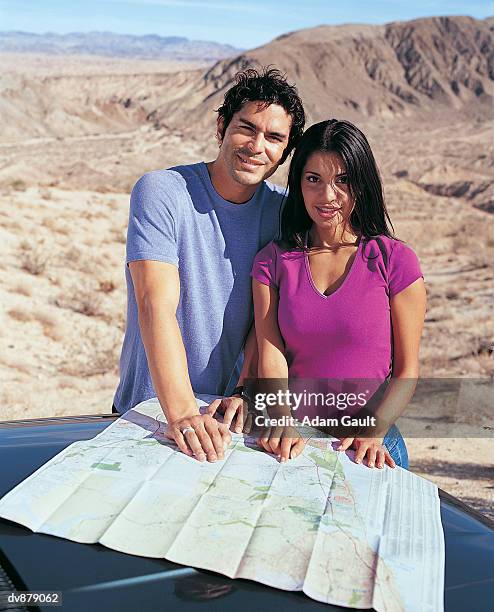 portrait of a couple with a map on a car bonnet - affe bildbanksfoton och bilder