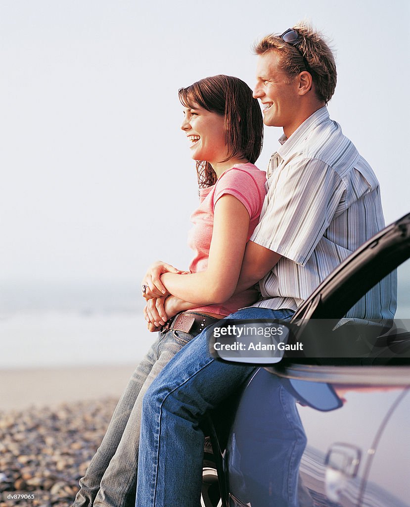 Couple at the Beach Looking at the View Standing Next to Their Car