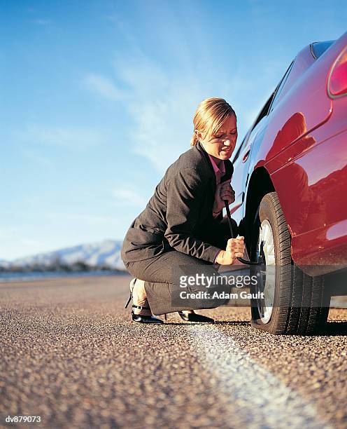 businesswoman repairing her punctured tyre - とらわれの姫 ストックフォトと画像