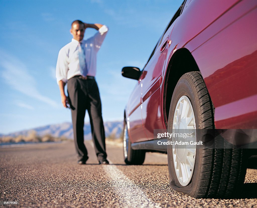 Businessman Standing by a Car With a Punctured Tyre