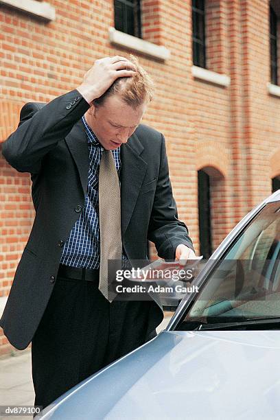 businessman with his hand on his head reading a parking ticket - parking violation stock pictures, royalty-free photos & images