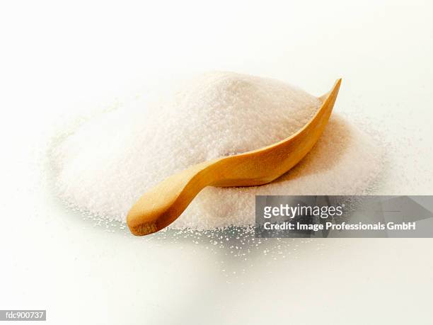 a pile of granulated sugar with wooden scoop - granulated sugar stock pictures, royalty-free photos & images
