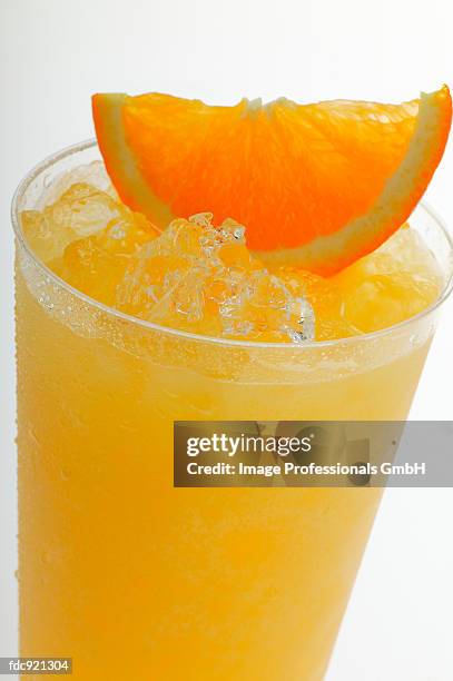 orange juice with crushed ice and wedge of orange (close-up) - künstliches eis stock-fotos und bilder