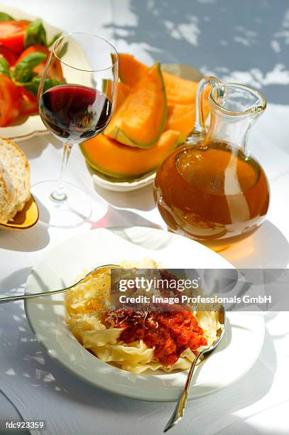 pasta with tomato sauce; sweet melon; wine; tomato salad - savory sauce fotografías e imágenes de stock