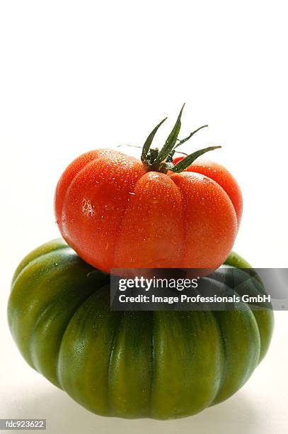 green and red beefsteak tomato with drops of water - beefsteak tomato stock pictures, royalty-free photos & images