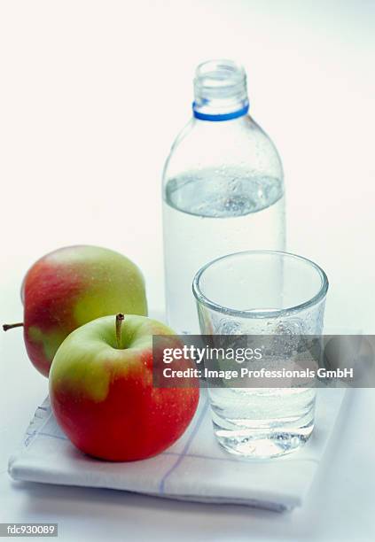 a bottle and a glass of mineral water, apples beside them - water apples stock pictures, royalty-free photos & images