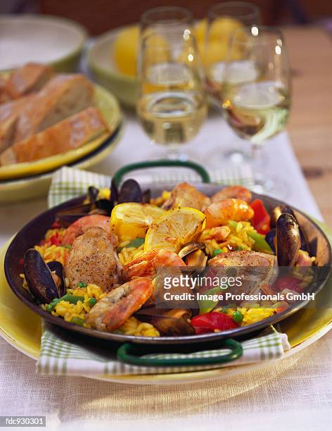 classic paella in paella pan on laid table - pan stock-fotos und bilder